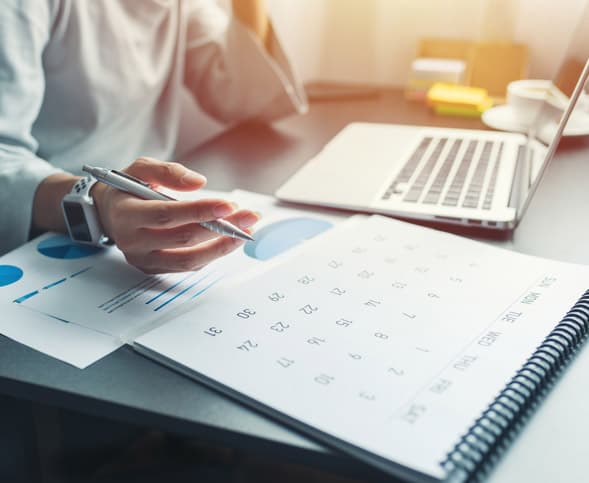 Business woman sitting working and thinking to plan event with calendar and laptop