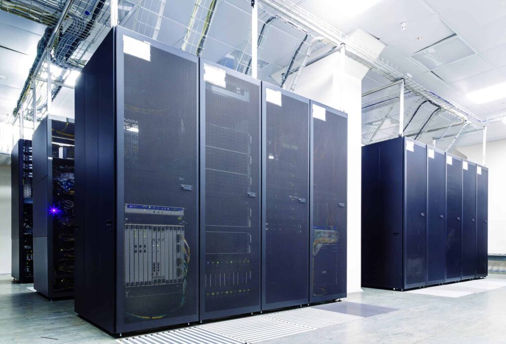 A modern data center featuring rows of black server racks with visible cabling and network equipment, illustrating high-capacity computing and data storage infrastructure.